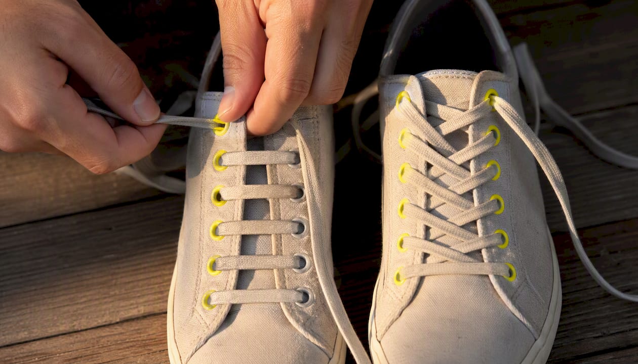 Hands demonstrating shoe lacing patterns