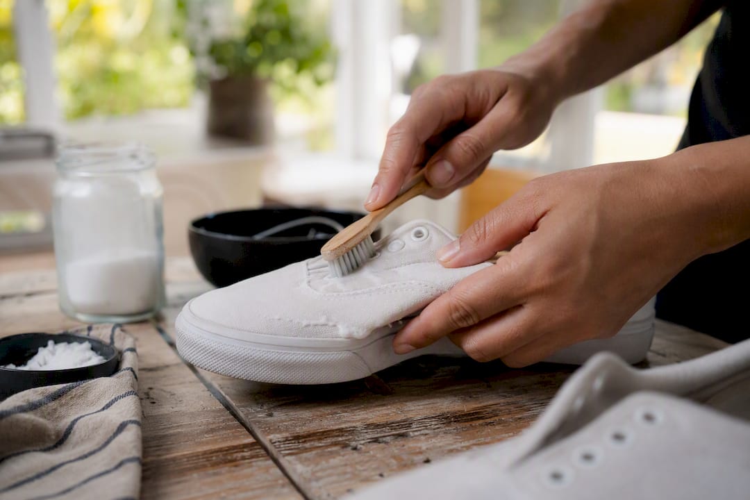 Applying baking soda paste with toothbrush on canvas shoe