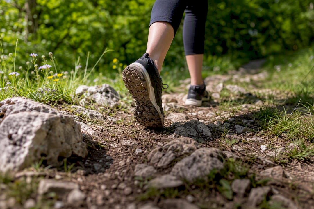 Foot in shoe stepping on uneven forest trail