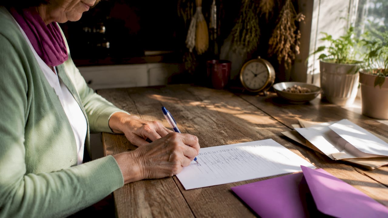 Hands marking mailing checklist on desk