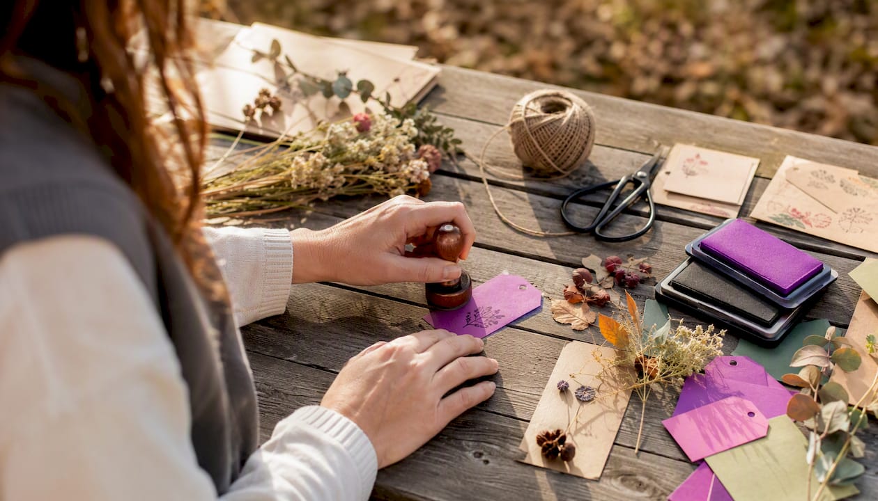 Hands stamping a gift tag in craft setting