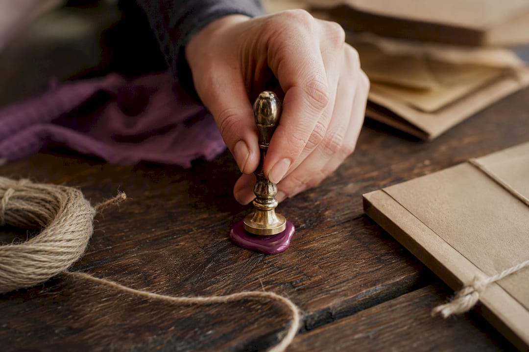 Hand pressing metal wax seal stamp on melted wax
