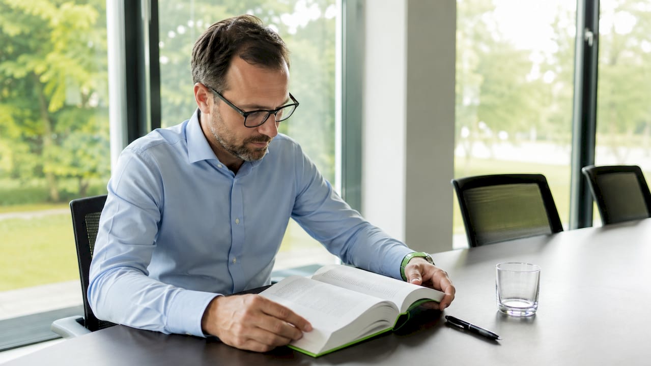 Ein Wissenschaftler arbeitet mit medizinischen Fachbüchern und recherchiert zusätzlich am Laptop.