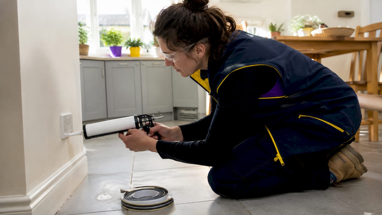 Home energy auditor sealing electrical socket gaps
