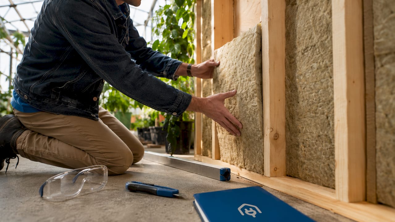 Hands installing insulation in UK home attic