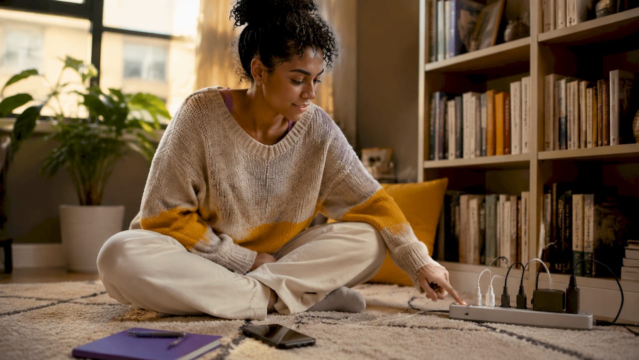 Woman turning off wall power strip in living room