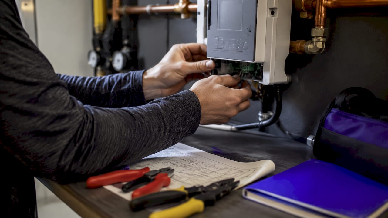 Hands installing heat pump control unit