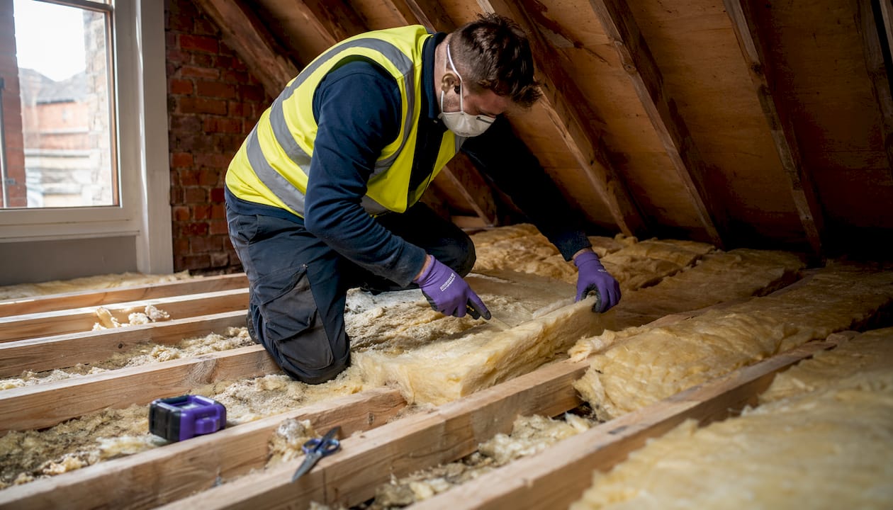 Installer placing loft insulation in attic