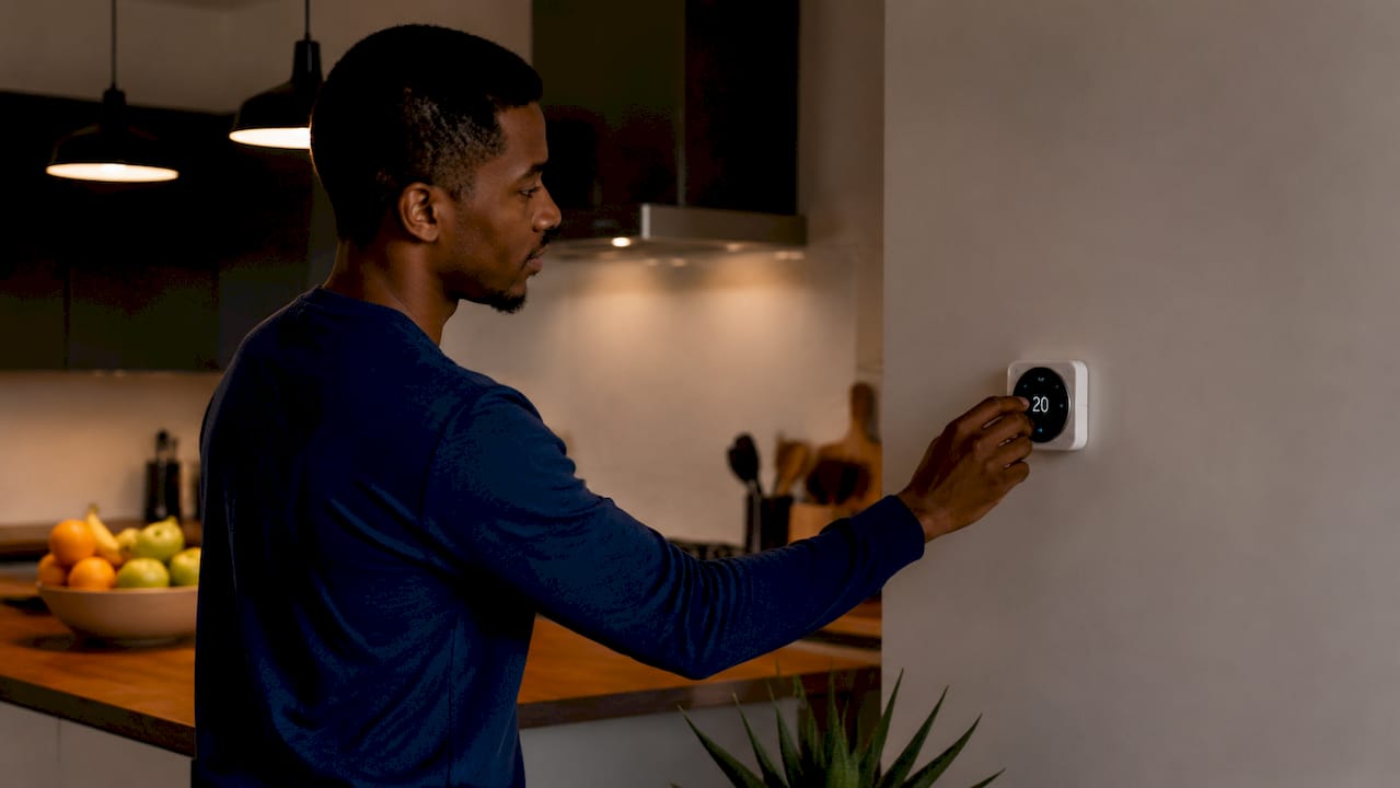 Man adjusting smart thermostat indoors