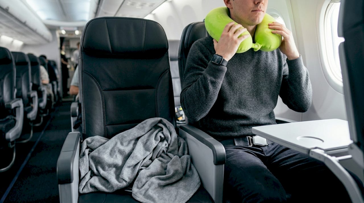 Traveler adjusting neck pillow in airplane window seat