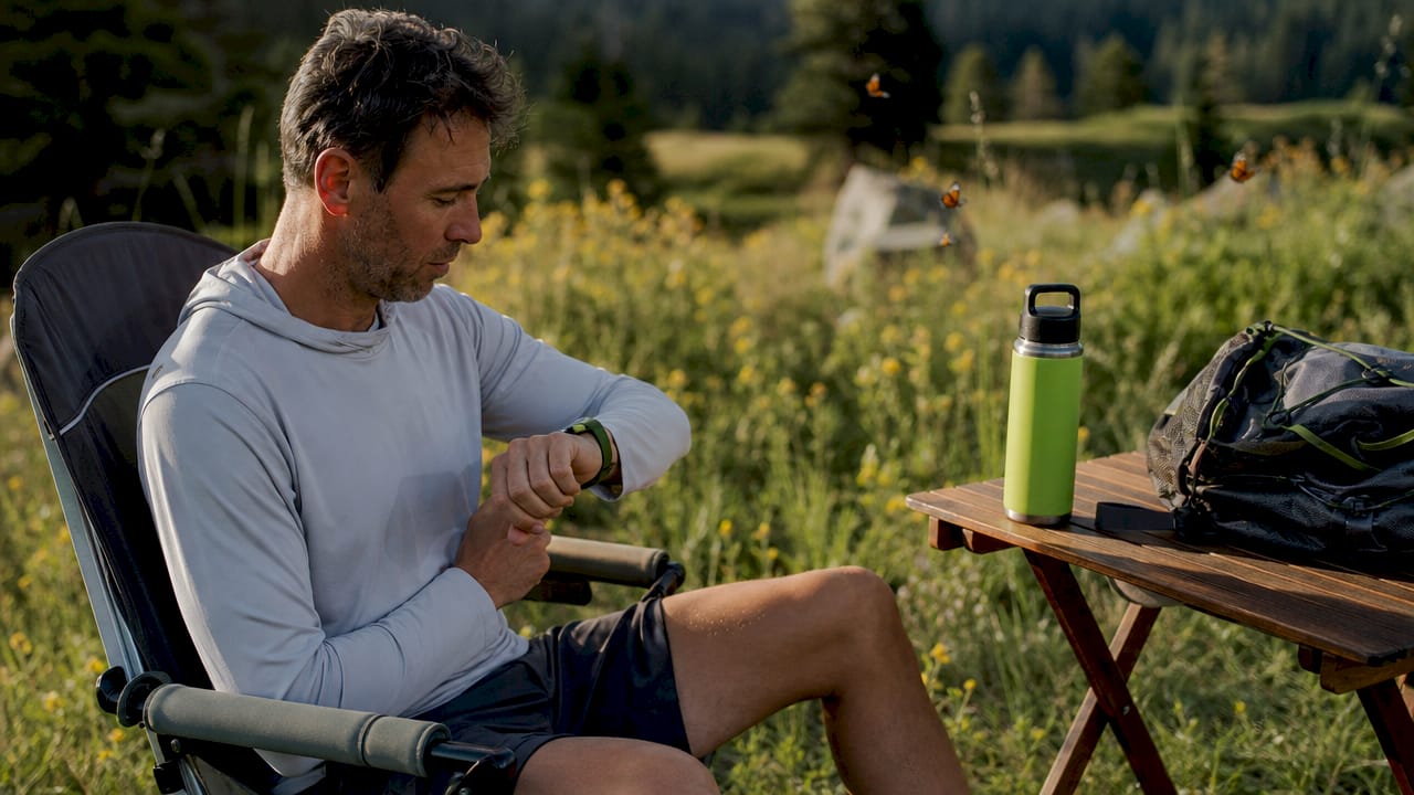 Man checking wearable comfort tech while seated outdoors