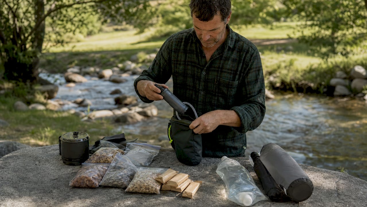 Hands packing backpacking food and water kit outdoors