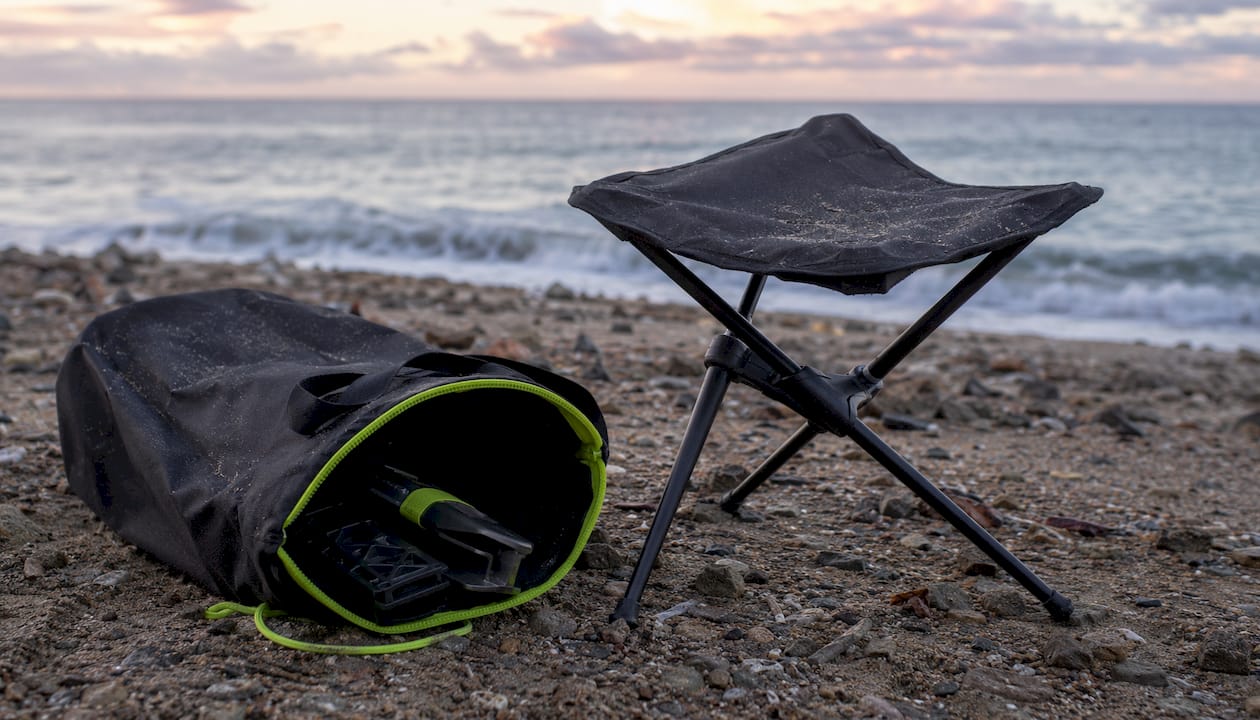 Compact portable camping stool on sandy beach