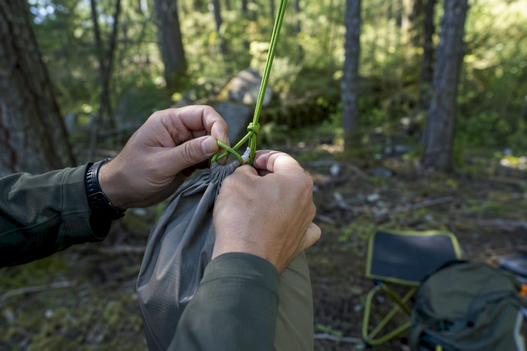 Hands tying food bag for bear hang in woods