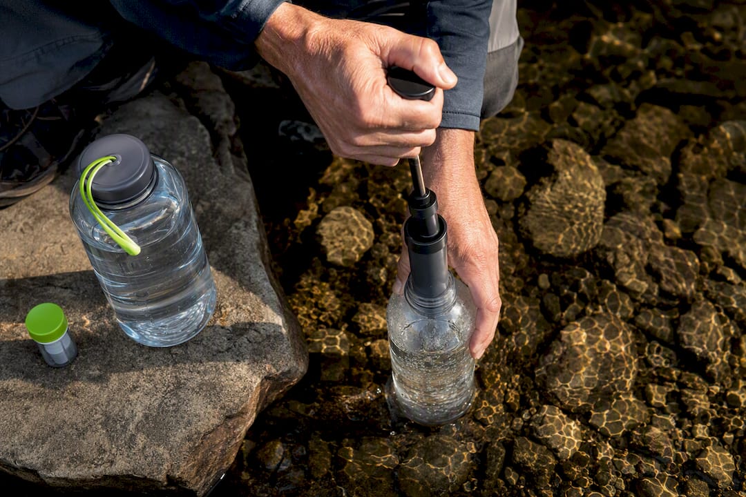 Hiker filtering stream water into bottle
