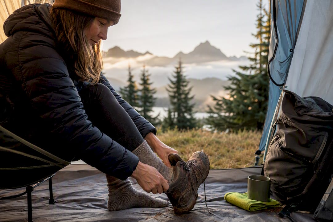 Camper removing boots beside tent entrance