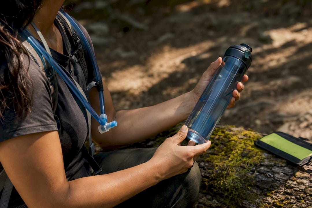 Hiker checking bottle beside hydration hose