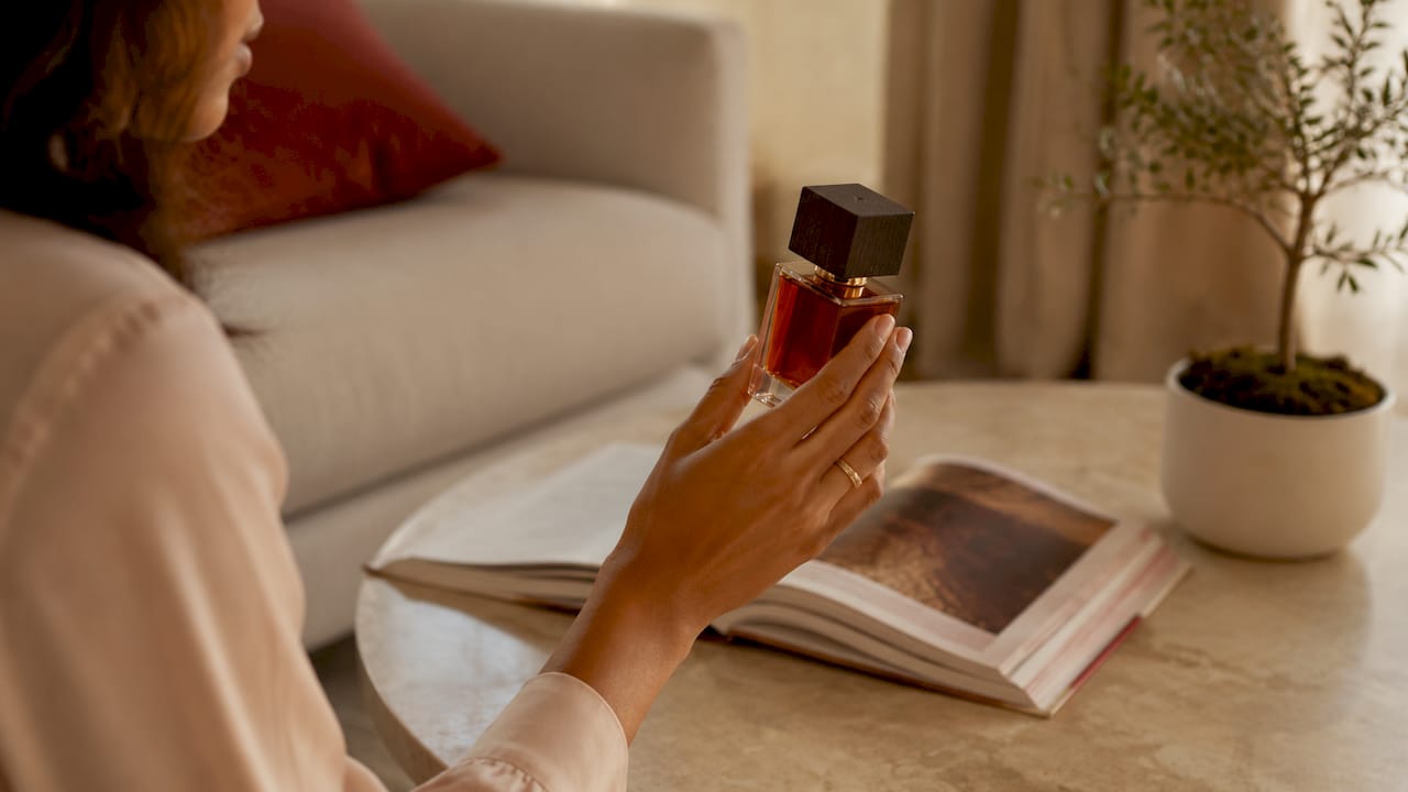 Detailopname van een hand met een vintage parfumflesje