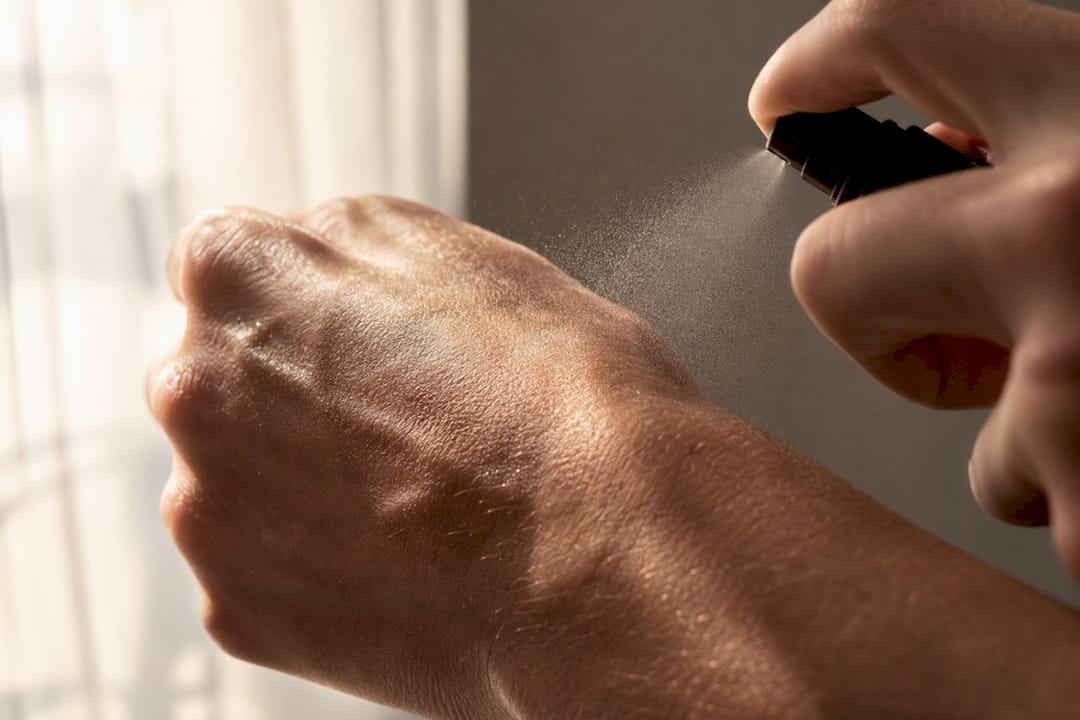 Een close-up van parfum die op een warme onderarm wordt gesprayd.