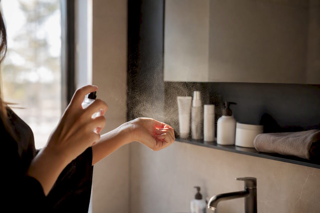Hand die parfum op de pols sprayt met nevel