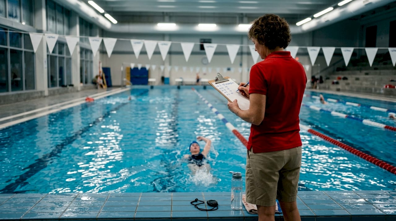 Coach analyzing swimmer’s stroke from poolside