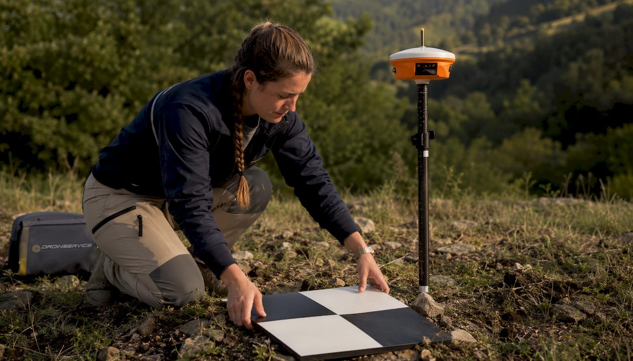 Un tecnico sta posizionando un punto di controllo a terra all'aperto.
