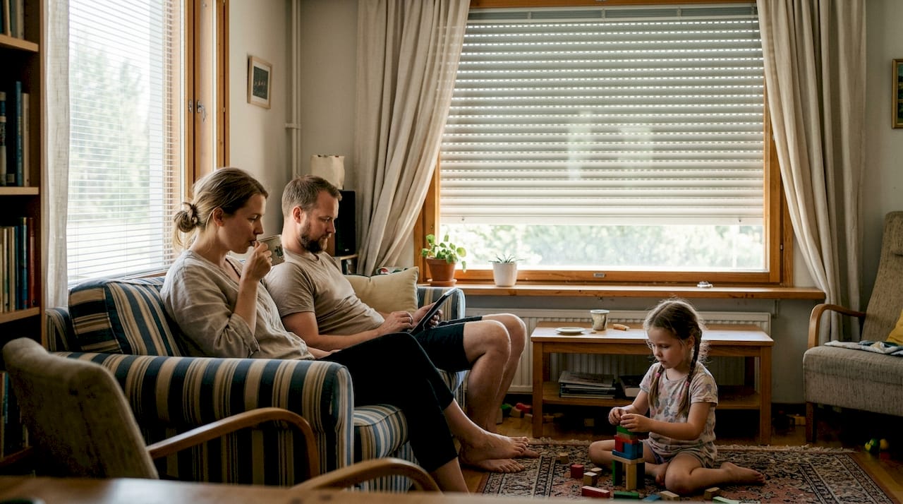 Perhe viettää aikaa olohuoneessa, jossa ulkorullaverhot on laskettu alas.