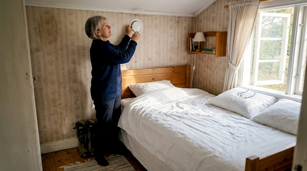 En kvinna justerar luftventilen i sovrummet.