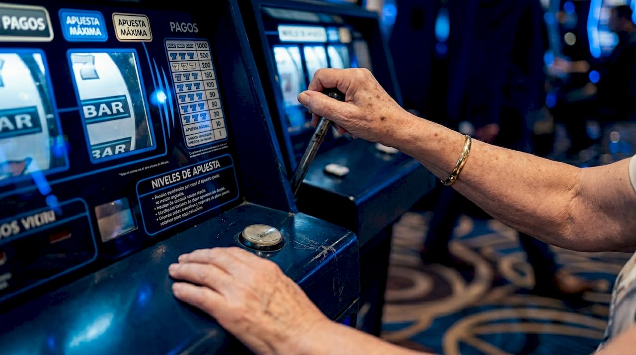 Unas manos accionando una máquina tragaperras en el casino