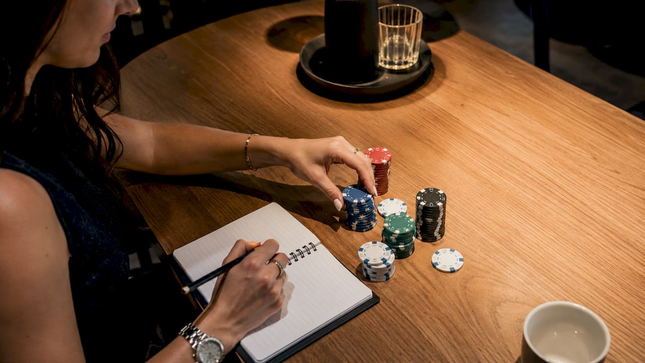 Detalle de unas manos manejando fichas y una calculadora sobre la mesa de un casino