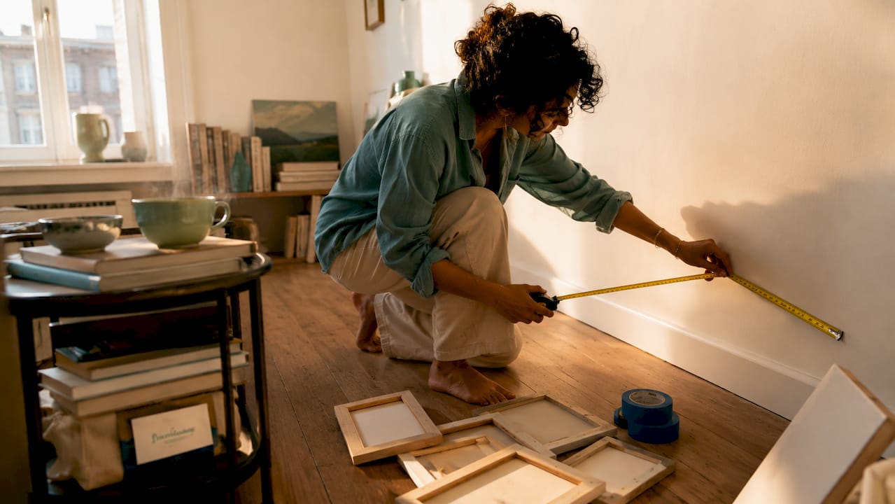 Person measuring wall space for gallery wall
