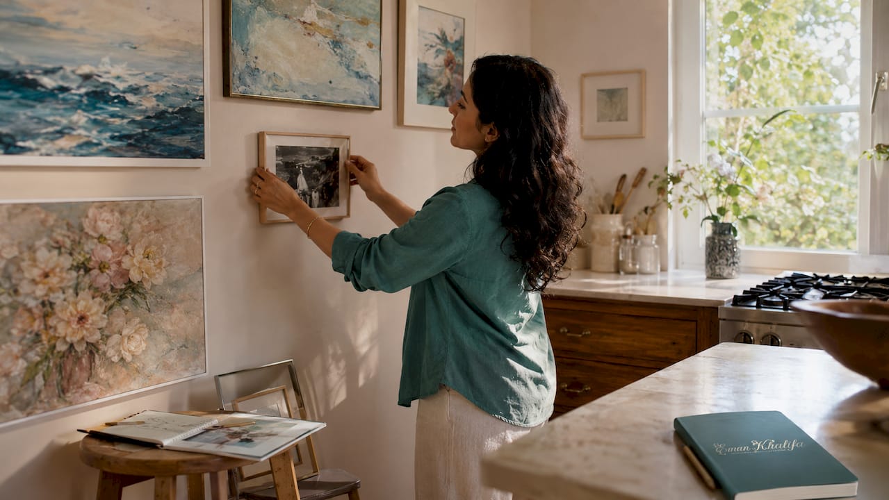 Woman arranging gallery wall frames in living room