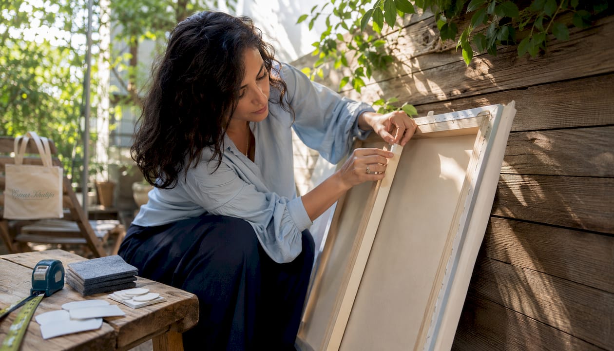 Woman applying adhesive strip to canvas corner