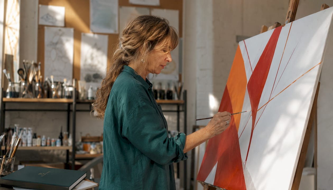 Hands painting geometric lines on canvas