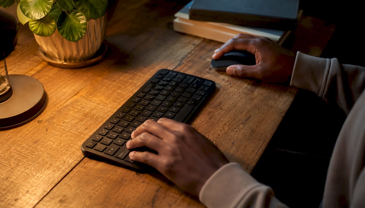 Unas manos trabajando con el teclado y el ratón sobre un escritorio de estilo minimalista.