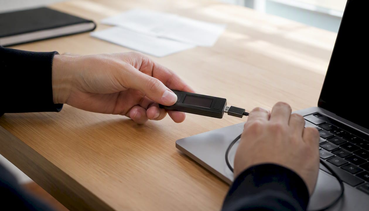 Unas manos vinculan una billetera de criptomonedas sobre el escritorio.