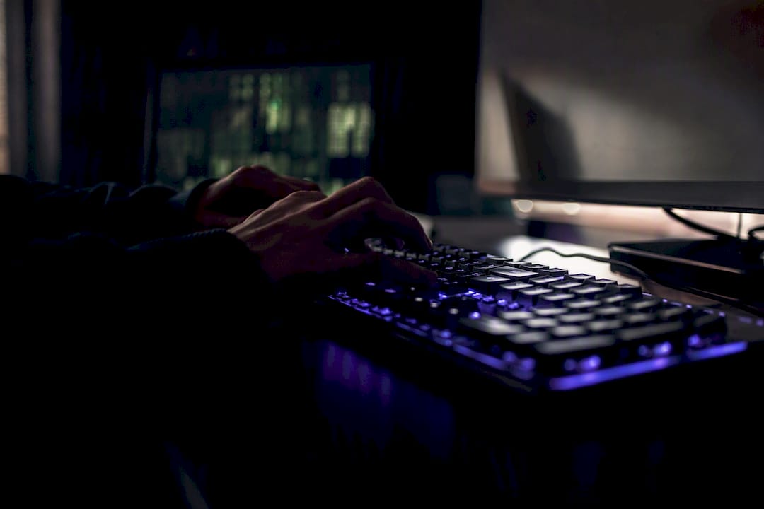 Manos escribiendo en un teclado mientras se despliega código digital en la pantalla