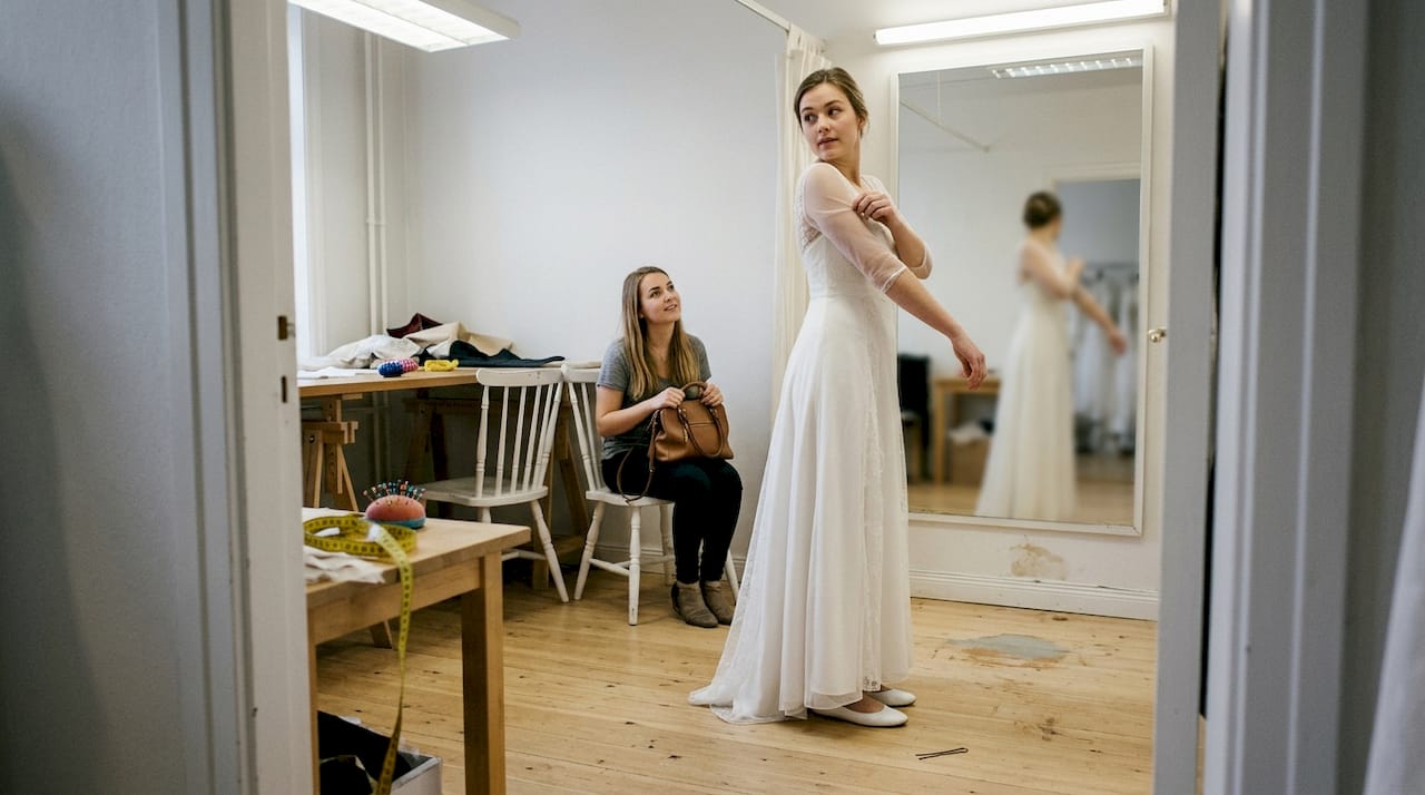 Een bruid bekijkt zichzelf in haar trouwjurk voor de grote spiegel in het atelier.