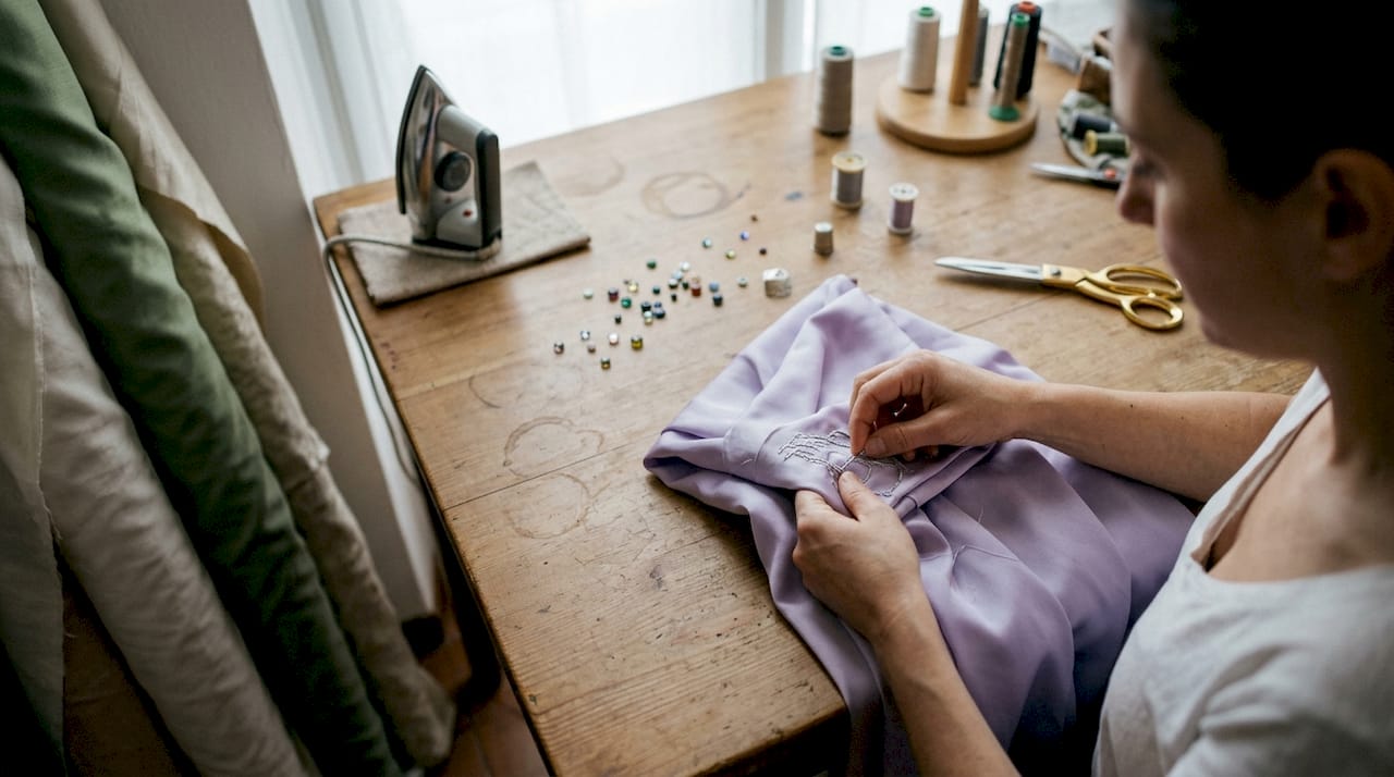 Maestri artigiani impreziosiscono abiti couture in seta con ricami raffinati e dettagli unici.