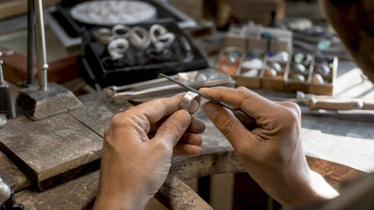 Abili mani di artigiano danno forma a un anello dalle linee geometriche.