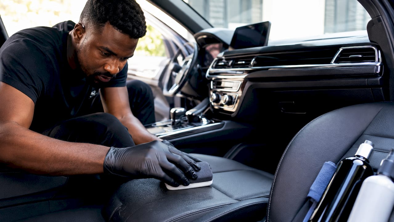 Close-up of hands conditioning car seat leather