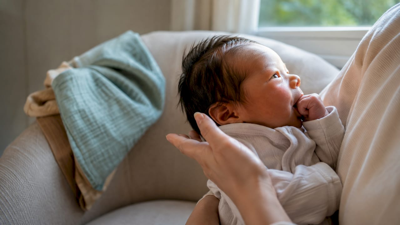 Newborn showing rooting and hand-to-mouth hunger cues