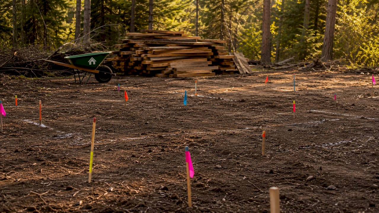 Cleared and levelled cabin building site with utility markers