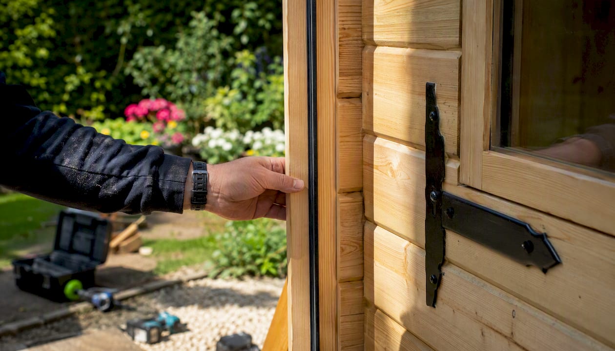 Close-up of hand inspecting door seal on garden cabin delivery