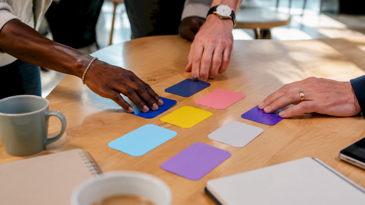 Des mains disposent des prototypes de boutons d’appel à l’action sur une table en verre.