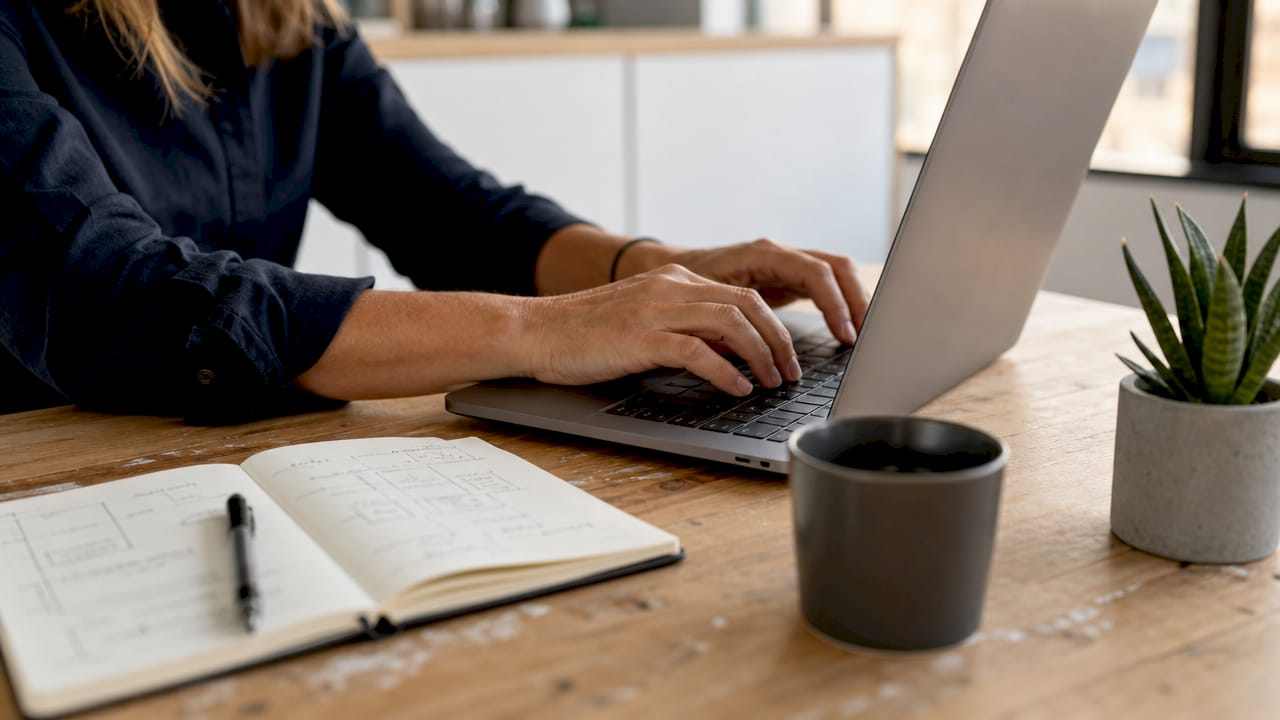 Rédaction de notes d’audit SEO sur un ordinateur portable, mains au clavier
