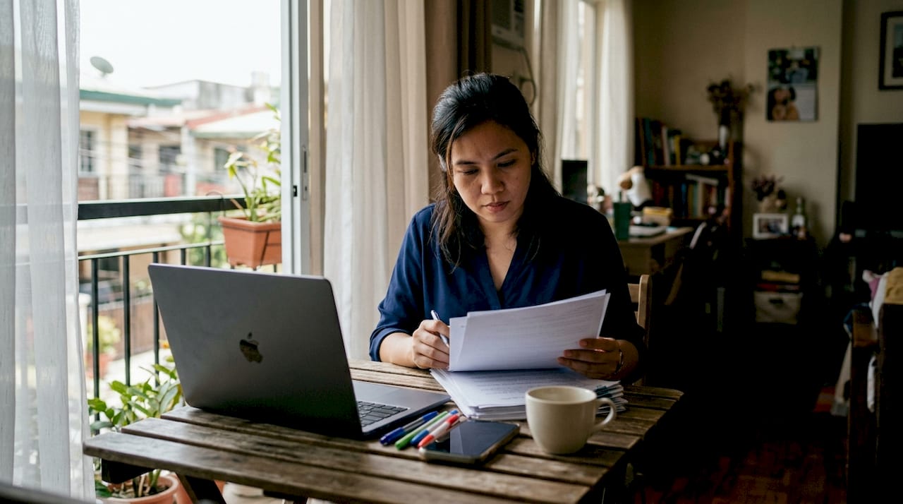 Filipino woman reviewing official documents at home
