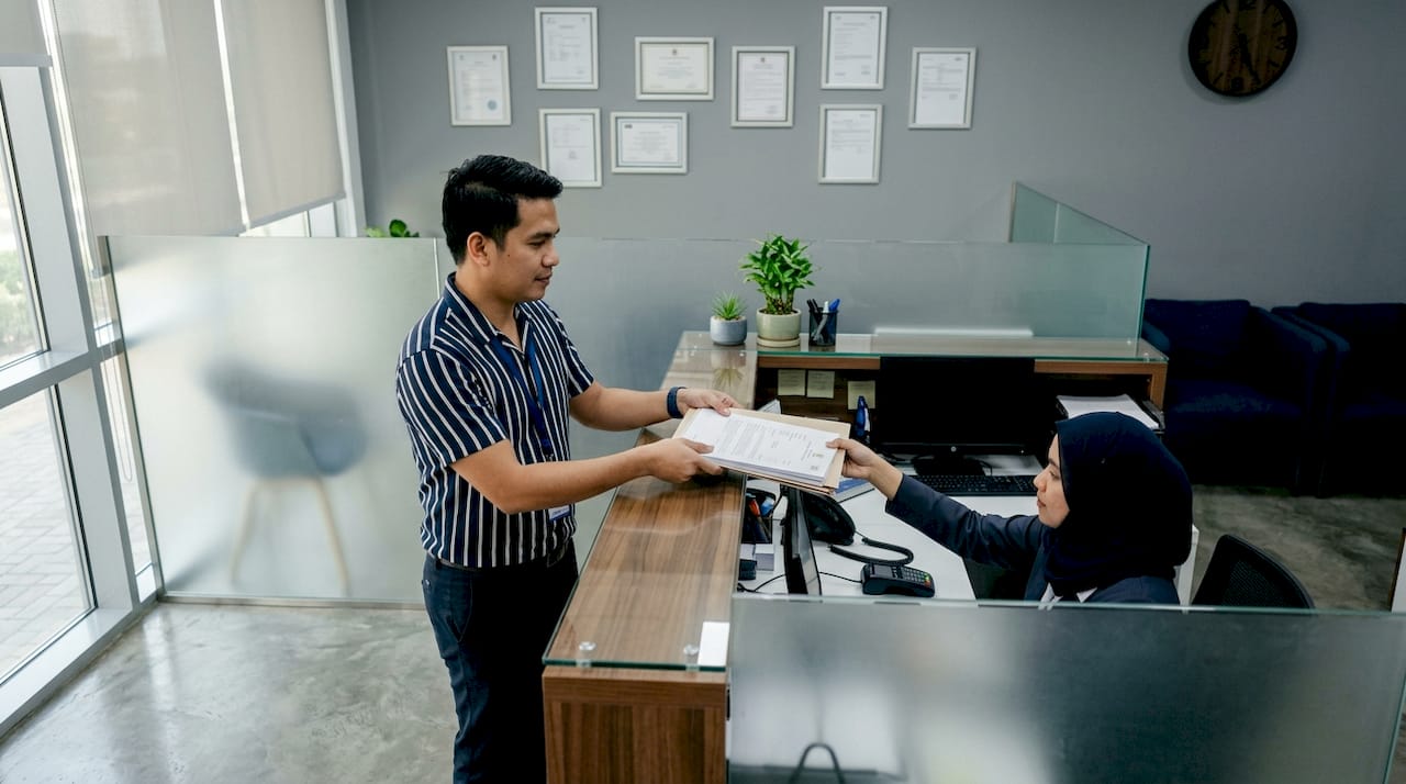 Filipino expat handing official documents at service desk