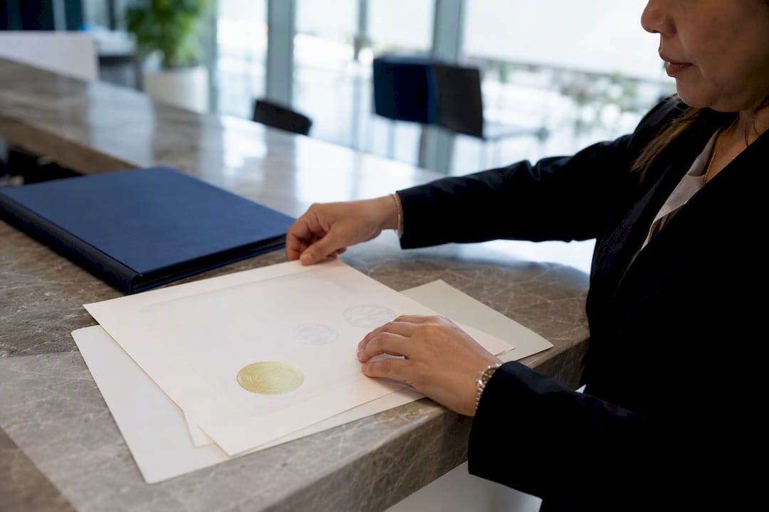 Hands placing stamped diploma on desk
