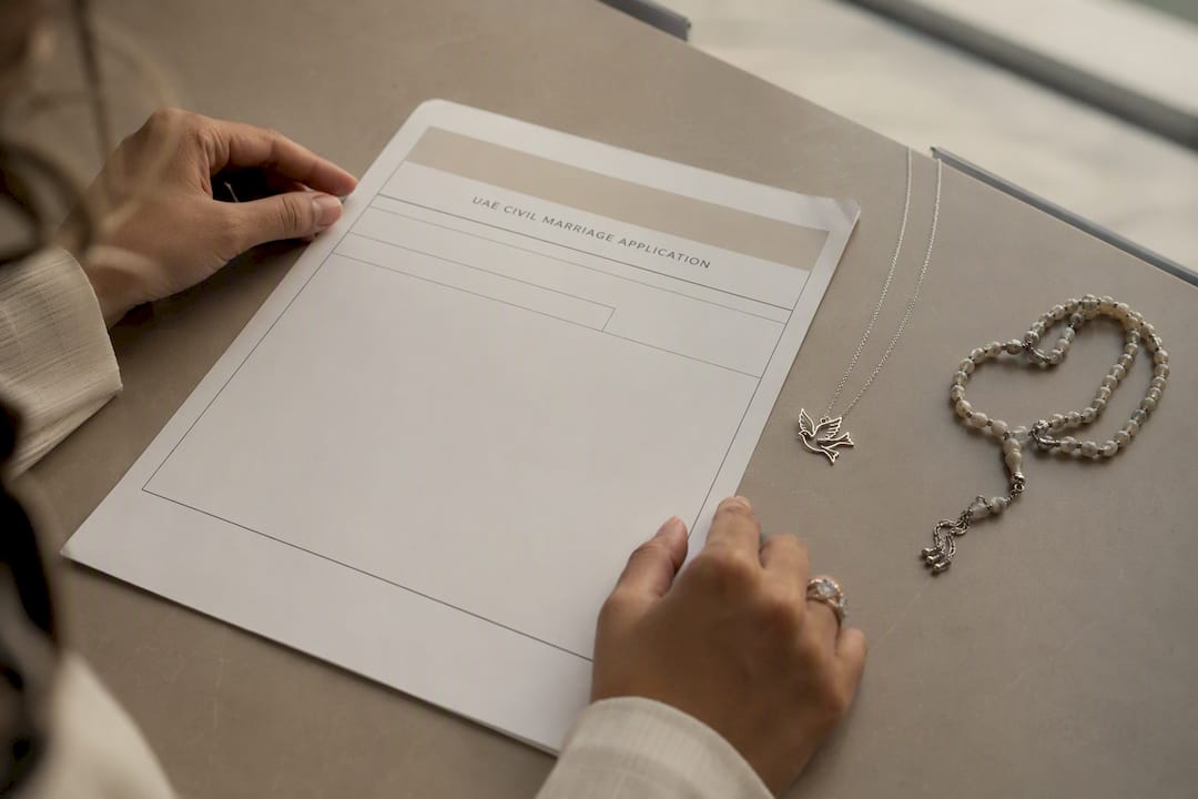 Hands arranging interfaith marriage paperwork and religious symbols